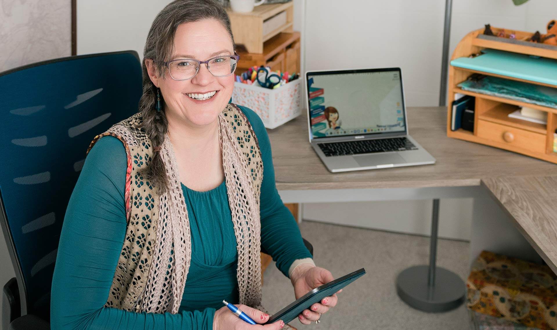 Nicole Lux-Ritche smiling and holding her phone at her desk in Luxcentric office