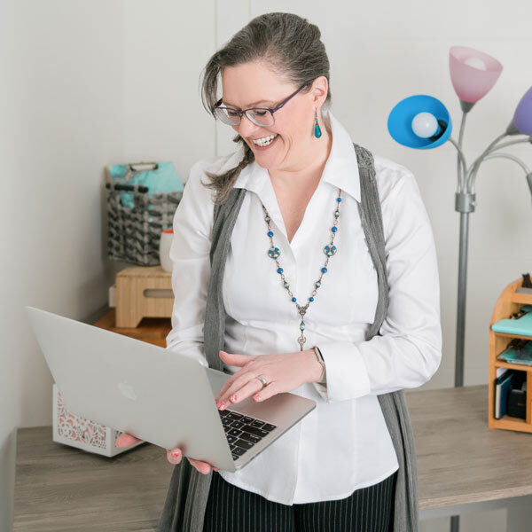 Nicole Lux-Ritchie looking at a laptop and smiling